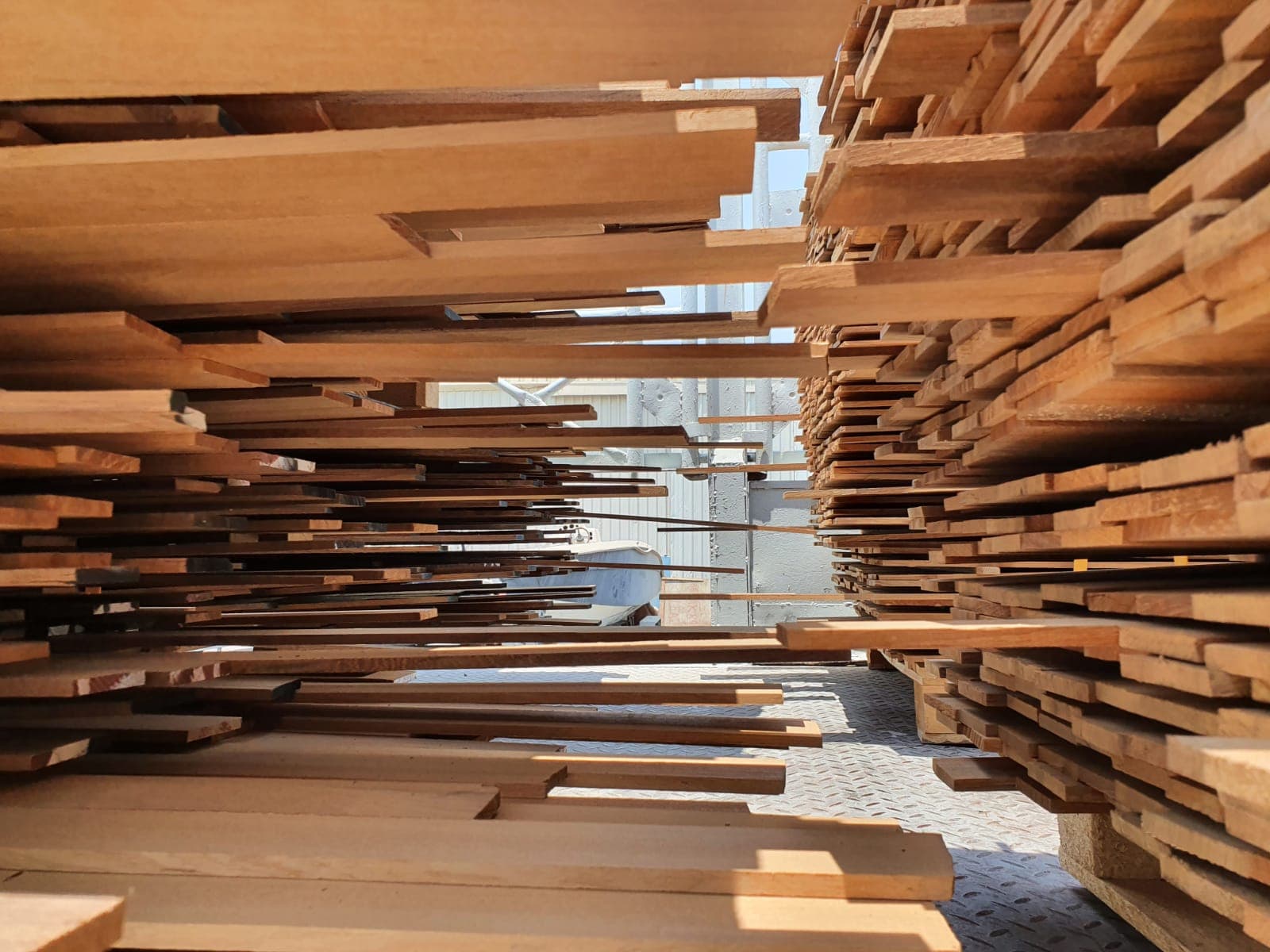 Symmetrical stacks of thin wooden planks create a tunnel-like perspective in an industrial setting.